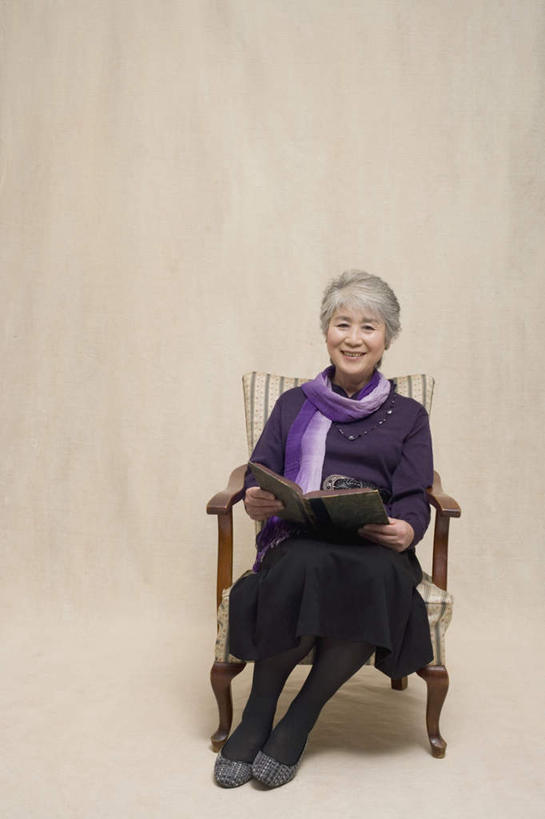 东方人,一个人,坐,笑,微笑,露齿笑,竖图,室内,白天,正面,看书,阅读,书籍,椅子,亚洲,仅一个女性,仅一个人,握,学习,米色背景,服装,装饰,木椅,拿,拿着,注视,休闲装,黄种人,衣服,紫色,围巾,书本,观察,看,休闲,温暖,休闲服,读书,浏览,握着,摄影,服饰,仅一个老年女性,影棚,围脖,观看,保暖,华丽,点缀,察看,御寒,关注,衬托,美观,雅致,雅观,老年女性,女人,女性,亚洲人,书,图书,坐着,彩图,全身,影棚拍摄,拍摄