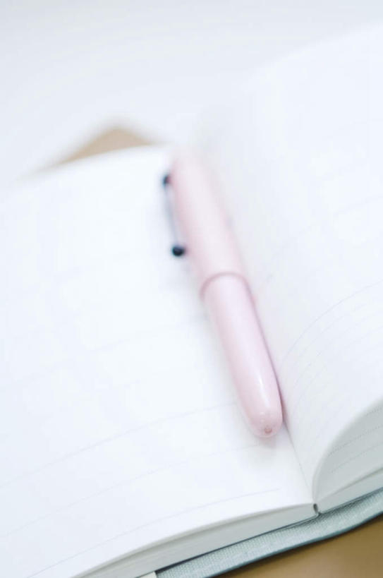 无人,竖图,俯视,室内,特写,白天,桌子,阴影,朦胧,模糊,光线,笔,影子,办公桌,办公用品,钢笔,记事本,文具,粉色,阳光,本子,笔记本,学习用品,打开,文具用品,一支,开启,彩图,高角度拍摄