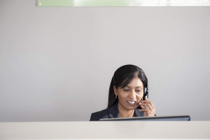 一个人,商务人士,商务女性,办公室,坐,笑,微笑,露齿笑,横图,室内,白天,正面,通讯,客服,电脑,显示器,鼠标,键盘,亚洲,仅一个女性,仅一个人,套装,网络,信息,墙,话务员,注视,输入设备,通讯设备,墙壁,墙面,耳机,耳麦,话筒,观察,看,仅一个中年女性,台式电脑,服务,通信,观看,协调,察看,麦克风,头戴式耳麦,关注,销售,通信设备,商务装,工薪阶层,输出设备,客服人员,电话销售,接待员,女人,女性,中年女性,亚洲人,印度人,白领,接线员,上班族,坐着,半身,彩图,头戴式耳机