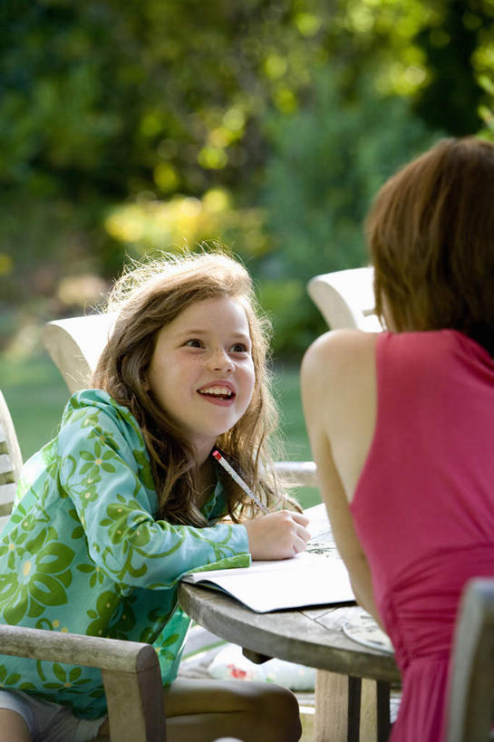 西方人,儿童,中年人,背部,两个人,家庭,母亲,女儿,坐,笑,微笑,露齿笑,竖图,室外,白天,正面,纯洁,树林,植物,桌面,桌子,书籍,椅子,欧洲,欧洲人,握,阴影,服装,朦胧,模糊,光线,木制,笔,影子,木椅,办公用品,记事本,拿,拿着,注视,休闲装,水笔,文具,树,树木,小孩,衣服,红色,绿色,阳光,自然,本子,笔记本,木制品,学习用品,看,休闲,温暖,温馨,母女,一家人,休闲服,可爱,母爱,童年,童趣,握着,服饰,生长,成长,文具用品,和睦,关注,童真,烂漫,无邪,天真,女孩,女人,女性,中年女性,白种人,孩子,书,图书,抬头,仰头,坐着,半身,彩图,融洽,女生