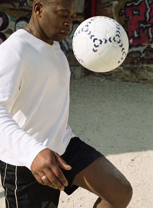 西方人,一个人,竖图,室外,白天,侧面,锻炼,运动,足球,欧洲,非洲,黑人,欧洲人,仅一个男性,仅一个人,踢,阴影,光线,影子,墙,足球装备,抬腿,运动器械,墙壁,墙面,仅一个年轻男性,阳光,健身器械,室外运动,健身器材,户外运动,蹴鞠,足球运动,男人,男性,年轻男性,非洲人,半身,彩图,健身,运动器材