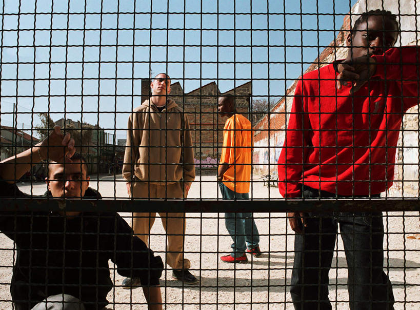 西方人,四个人,伙伴,朋友,家,栏杆,站,举,横图,室外,白天,正面,锻炼,友谊,运动,树林,植物,欧洲,非洲,黑人,欧洲人,阴影,光线,影子,房屋,墙,屋子,围栏,地面,注视,护栏,楼房,墙壁,墙面,住宅,树,树木,蓝色,绿色,蓝天,天空,阳光,自然,天,看,靠,靠着,托,站着,生长,晴朗,成长,观看,关注,室外运动,户外运动,万里无云,双手抄兜,双手放兜,友情,男人,男性,年轻男性,白种人,非洲人,晴空,晴空万里,插兜,举手,举着,两手抄兜,两手放兜,手插兜,手放口袋,向上举,向上伸,向上托,站立,半身,彩图,健身,涂鸦,房子,手抄兜