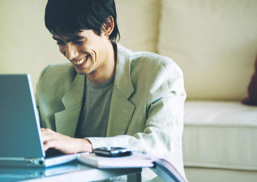 西方人,一个人,客厅,坐,笑,微笑,露齿笑,横图,室内,白天,正面,电脑,笔记本电脑,沙发,桌子,欧洲,欧洲人,仅一个男性,仅一个人,敲打,网络,办公桌,注视,输入,通讯设备,仅一个年轻男性,打字,观察,看,观看,点击,敲击,察看,无线,起居室,关注,通信设备,无线网络,无线上网,便携式电脑,按键,手提电脑,男人,男性,年轻男性,白种人,坐着,半身,彩图,皮沙发