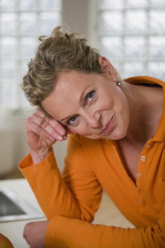 西方人,一个人,站,笑,微笑,竖图,室内,白天,正面,厨房,桌面,桌子,欧洲,欧洲人,仅一个女性,仅一个人,撑,服装,朦胧,模糊,木制,扭头,注视,休闲装,衣服,木制品,观察,看,站着,转头,仅一个中年女性,休闲,休闲服,服饰,观看,察看,撑着,关注,女人,女性,中年女性,白种人,站立,半身,彩图,灶间