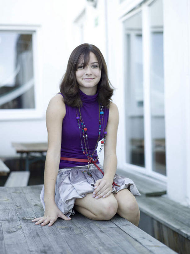 西方人,一个人,坐,笑,微笑,竖图,室外,白天,正面,裙子,窗户,落地窗,桌面,桌子,欧洲,欧洲人,仅一个年轻女性,仅一个女性,仅一个人,服装,木制,墙,注视,休闲装,玻璃窗,墙壁,墙面,衣服,木制品,观察,看,休闲,休闲服,短裙,服饰,观看,半身裙,察看,关注,年轻女性,女人,女性,白种人,坐着,彩图,全身