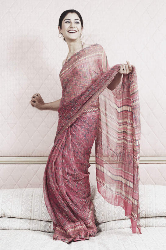 一个人,站,举,笑,微笑,露齿笑,竖图,室内,白天,正面,民族服装,床,卧室,亚洲,仅一个年轻女性,仅一个女性,仅一个人,墙,双人床,床单,注视,被子,墙壁,墙面,扶,观察,看,托,站着,服饰,观看,飘逸,察看,被单,扶着,庄重,关注,追求,纱丽,雅致,纱丽服,清婉,妍丽,年轻女性,女人,女性,亚洲人,印度人,举起,举手,举着,向上举,向上伸,向上托,站立,彩图,全身,传统服装,民俗服,睡房,卧房,奢华