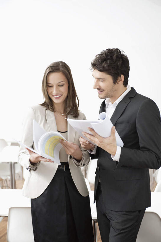 西方人,两个人,伙伴,朋友,商务人士,商务男性,商务女性,站,捧,笑,微笑,露齿笑,竖图,室内,白天,正面,衬衫,友谊,合作,团队,桌子,书籍,椅子,欧洲,欧洲人,套装,塑料,办公桌,墙,注视,墙壁,墙面,白色,塑料制品,观察,看,站着,战略,观看,察看,关注,商务装,工薪阶层,联合,合谋,配合,协作,男人,男性,年轻男性,年轻女性,女人,女性,白种人,白领,上班族,书,图书,端,端着,捧着,手捧,站立,半身,彩图,衬衣